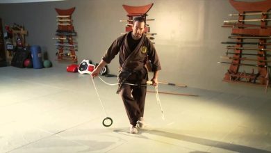 Illustration of a ninja wielding a kyoketsu-shoge rope with hooked blade mid-throw against a castle wall.