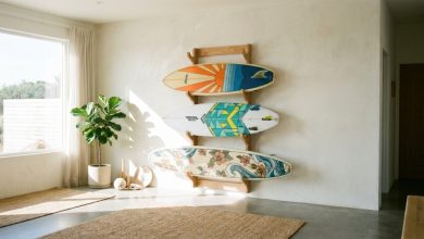 Three surfboards stand safely upright in a wooden indoor storage rack.