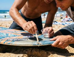 Person applying epoxy resin to fix a skimboard rail ding.
